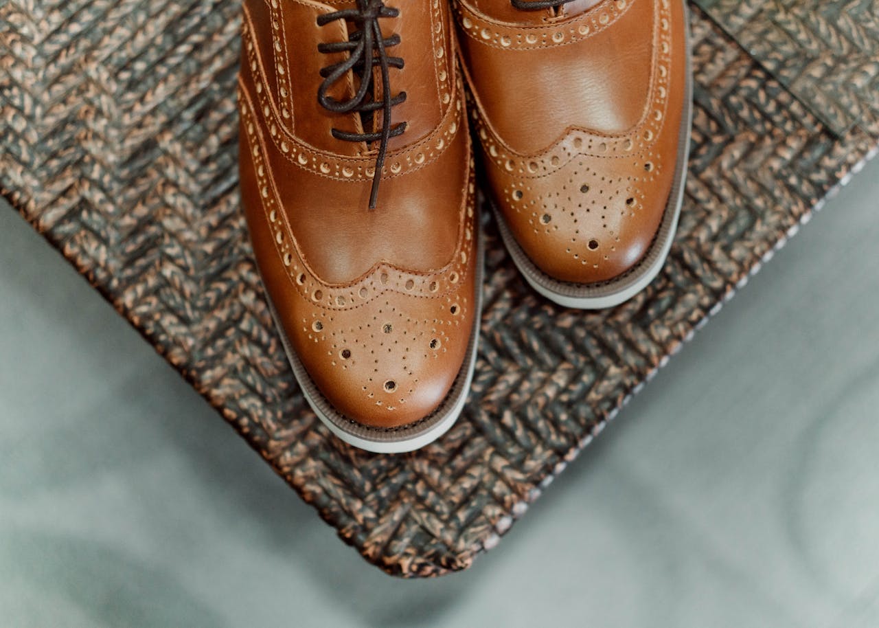 Services-03 A close-up of stylish brown leather brogues with intricate design on a wicker surface.